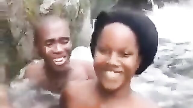 Topless ebony whore with naked breasts having fun with her boyfriend in a waterfall